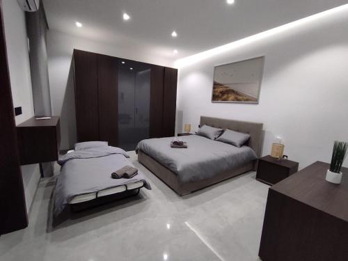 a large bedroom with two beds and a mirror at Flat 2, stay close to Countryside & Beaches in Mġarr