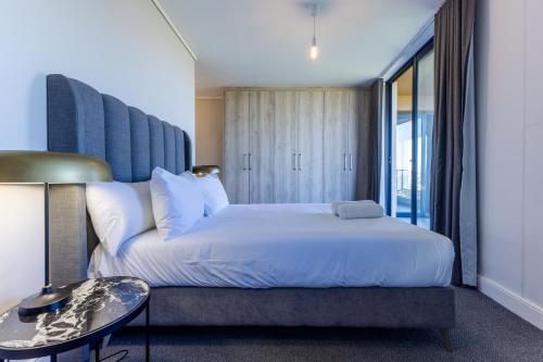 a bedroom with a large white bed and a table at Waters Edge Apartments in Cape Town