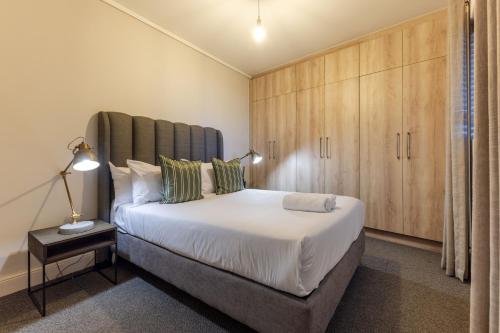 a bedroom with a large white bed and wooden cabinets at Waters Edge Apartments in Cape Town