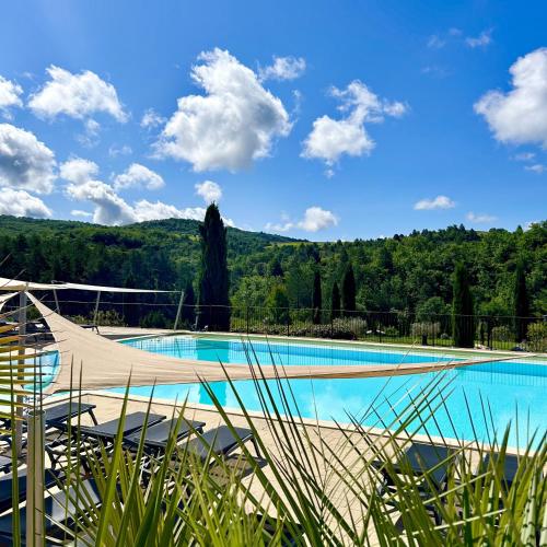 une piscine avec un hamac devant une montagne dans l'établissement Les Villas du Vendoule, à Saint-Maurice-dʼArdèche