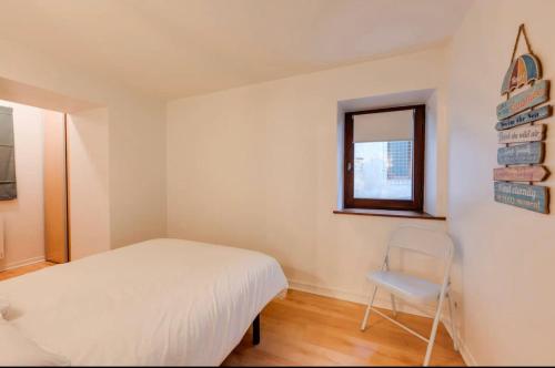 une chambre avec un lit, une chaise et une fenêtre dans l'établissement Cosy Paquier, à Annecy