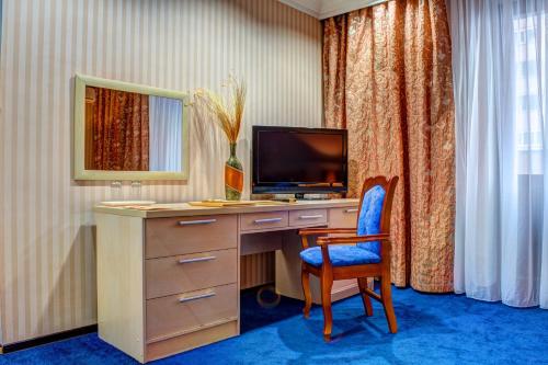 a room with a desk with a television and a chair at King Hotel Astana in Astana