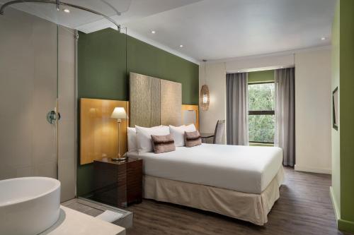a bedroom with a bed and a bathroom with a sink at Protea Hotel by Marriott Bloemfontein Willow Lake in Bloemfontein