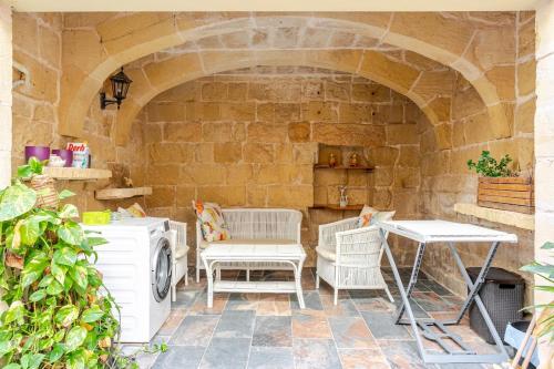 a patio with a table and chairs and a stone wall at Traditional entire maisonette close to airport in Birżebbuġa