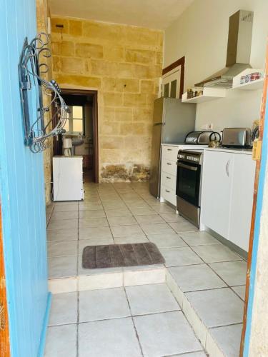 a kitchen with white appliances and a tile floor at Traditional entire maisonette close to airport in Birżebbuġa