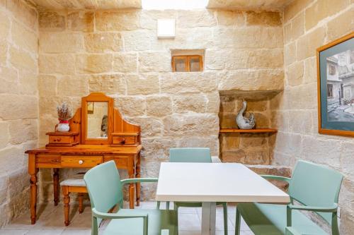 a stone walled room with a table and chairs at Traditional entire maisonette close to airport in Birżebbuġa