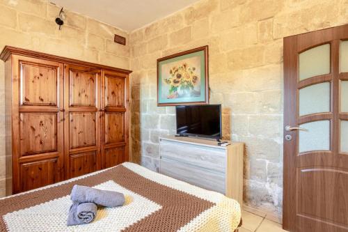 a bedroom with a bed and a tv and a door at Traditional entire maisonette close to airport in Birżebbuġa