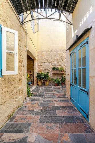 an alley with a blue door in a building at Traditional entire maisonette close to airport in Birżebbuġa