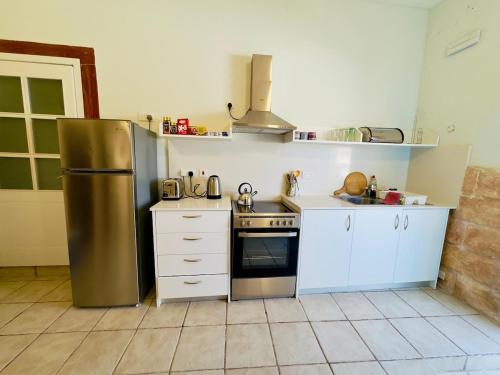 a kitchen with a stainless steel refrigerator and white cabinets at Traditional entire maisonette close to airport in Birżebbuġa