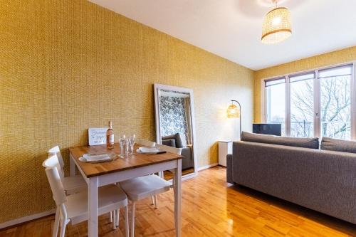 une salle à manger avec une table et un canapé dans l'établissement Appartement parking Dijon proche centre Wilson, à Dijon