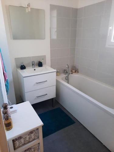 La salle de bains est pourvue d'une baignoire blanche, d'un lavabo et d'une baignoire. dans l'établissement La conviviale, à Bénouville