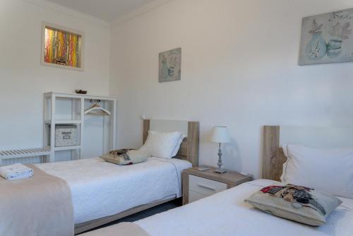 ein Schlafzimmer mit zwei Betten und einem Tisch mit Lampe in der Unterkunft Villa Figueira in Portimão