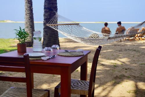 a table and chairs with a hammock on the beach at Mojo in Vannativillu
