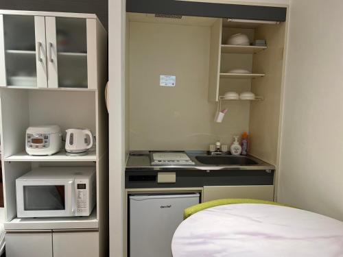 a small kitchen with a sink and a microwave at marron home 大阪 in Osaka