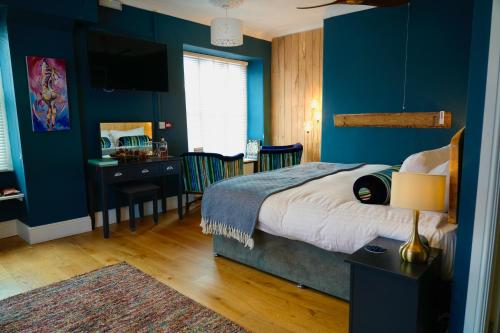 a bedroom with blue walls and a bed and a desk at Arosfa Harbourside Aberaeron in Aberaeron