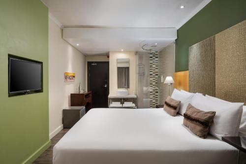 a bedroom with a large white bed and a television at Protea Hotel by Marriott Bloemfontein Willow Lake in Bloemfontein