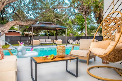 a patio with chairs and a table and a pool at 6 Bedrooms, Two Villas, Heated Pool, 2mil to Downtown in Naples