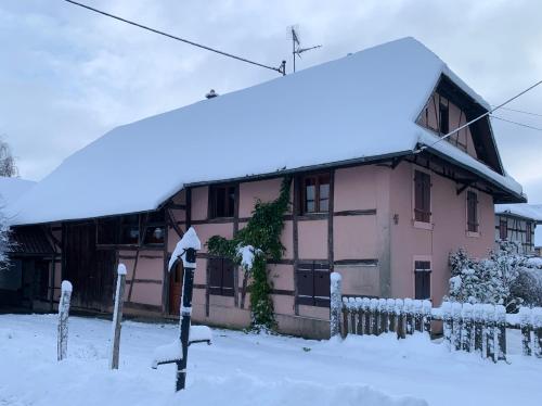 Soppe-le-HautにあるFerme alsacienneの雪の中に柵を持つピンクの家