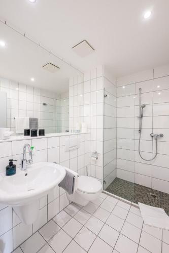 a white bathroom with a sink and a shower at Inselhotel Rügen in Göhren