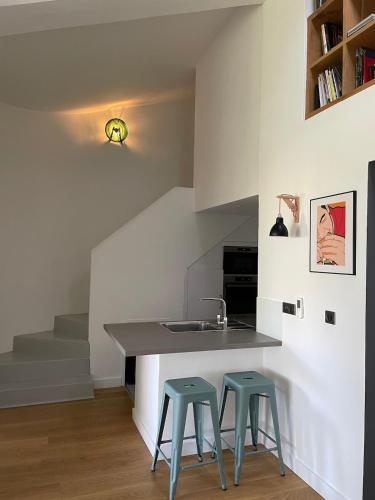 - une cuisine avec deux tabourets et un comptoir avec un évier dans l'établissement Très beau duplex, 2 chambres, parking privé, plage à 5 minutes, à Sainte-Maxime