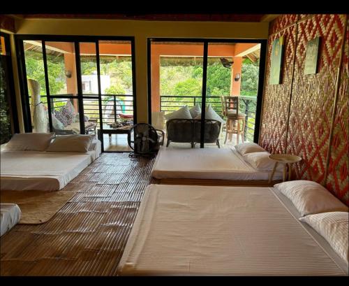 a room with three beds and a balcony with windows at KEHLANI Vacation Farmhouse in Hermosa