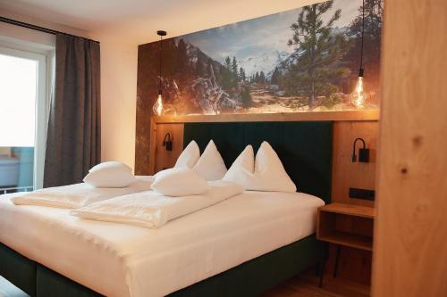 ein Schlafzimmer mit einem großen Bett mit weißen Kissen in der Unterkunft Gasthof Schütthof in Neukirchen am Großvenediger