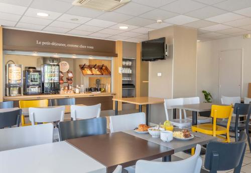 a restaurant with tables and chairs and a counter at B&B HOTEL Marseille Aéroport Saint-Victoret in Saint-Victoret