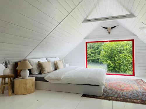 a white bedroom with a bed and a window at Chata Vlčanda 346 in Staré Křečany