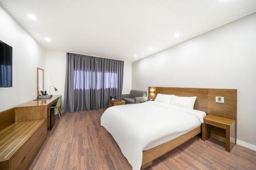 a hotel room with a large bed and a desk at The 7 Business Hotel in Gumi