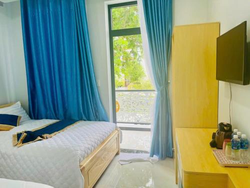 a bedroom with a bed with blue curtains and a window at Sand Sea Hotel in Phan Thiet