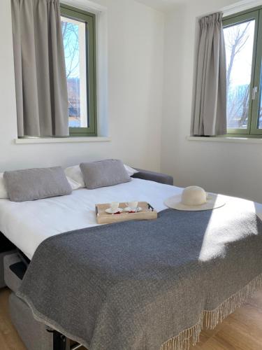 a bedroom with a bed with a hat and two windows at Innesti Rooms&Apartments - Gli Appartamenti in Pergine Valsugana