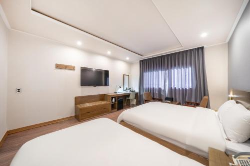 a hotel room with two beds and a television at The 7 Business Hotel in Gumi