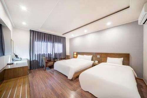 a hotel room with two beds and a desk at The 7 Business Hotel in Gumi