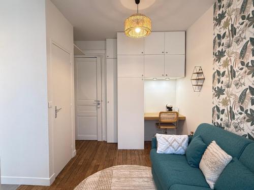 a living room with a blue couch and a table at Le Petit Nid - cozy comfort close to Paris in Clichy