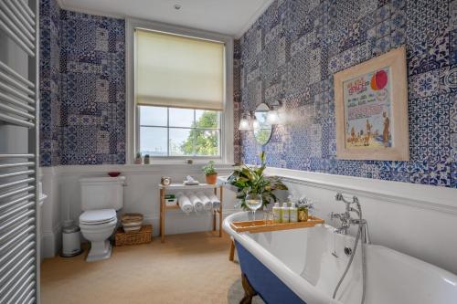 a bathroom with blue and white wallpaper and a tub at Norfolk House Hosted by The Scarlet Hen in Huddersfield