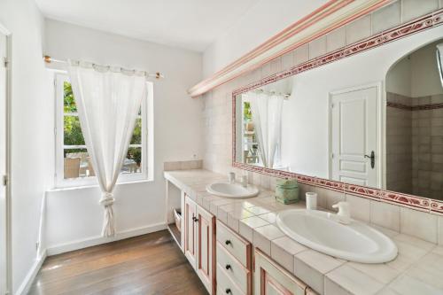 une salle de bain avec deux lavabos et un grand miroir dans l'établissement Villa La Désirade - LES PIEDS DANS L'EAU - PLAGE LA BOUILLABAISSE - ST TROPEZ - 14 PERSONNES, à Saint-Tropez