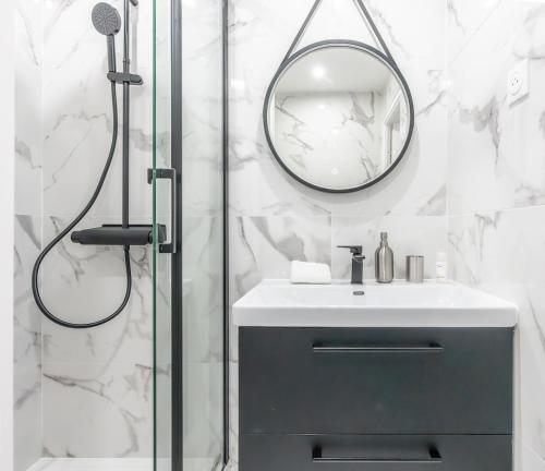 une salle de bain avec un lavabo et une douche avec un miroir dans l'établissement Disney à Paris - Fontaine Rouge, à Chessy