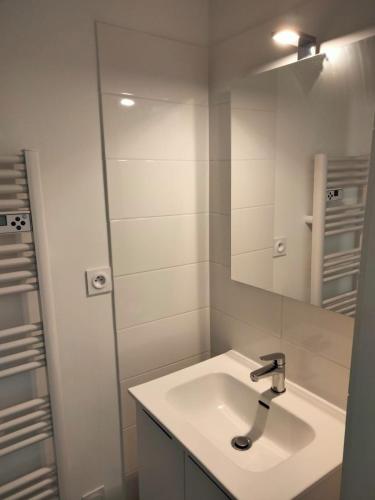 une salle de bain blanche avec un lavabo et un miroir dans l'établissement Le Rouget de Lisle proche gare, à Agen