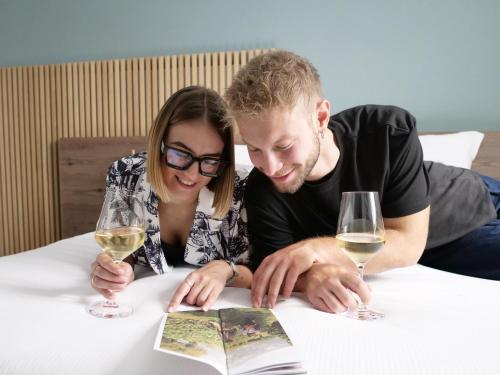 a man and woman sitting at a table with wine glasses at Innesti Rooms&Apartments - Le camere in Pergine Valsugana