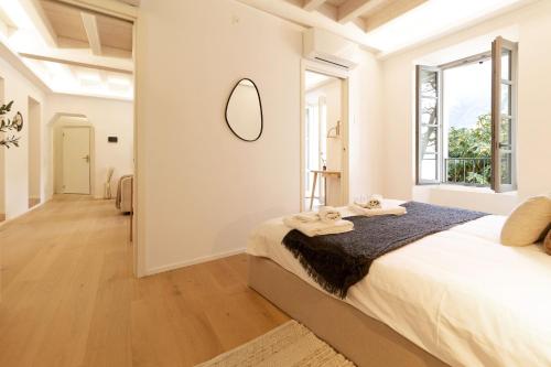 a white bedroom with a large bed and a mirror at Luxury flat by the lake in Morcote