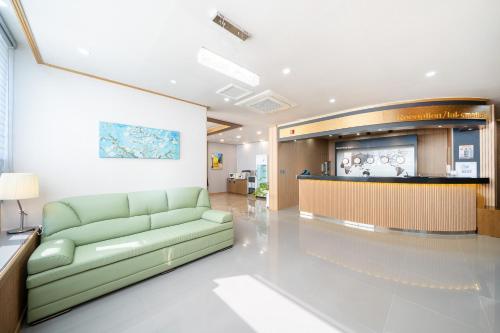 a living room with a green couch in a lobby at The 7 Business Hotel in Gumi
