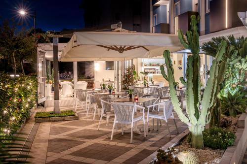 a patio with tables and chairs and an umbrella at All'Orologio - Boutique Hotel in Caorle