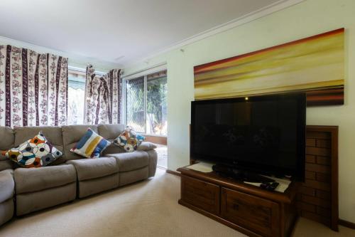 a living room with a couch and a flat screen tv at Well equipped 3BR Home with Backyard and Patio in Perth