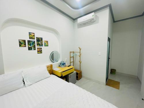 a bedroom with a white bed and a yellow desk at Sand Sea Hotel in Phan Thiet
