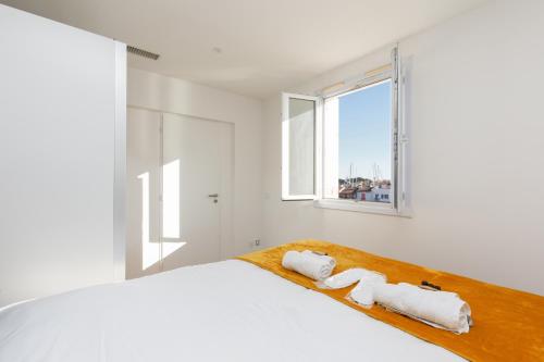 une chambre blanche avec un lit avec des serviettes dessus dans l'établissement L'Ammarage YourHostHelper, à Grimaud
