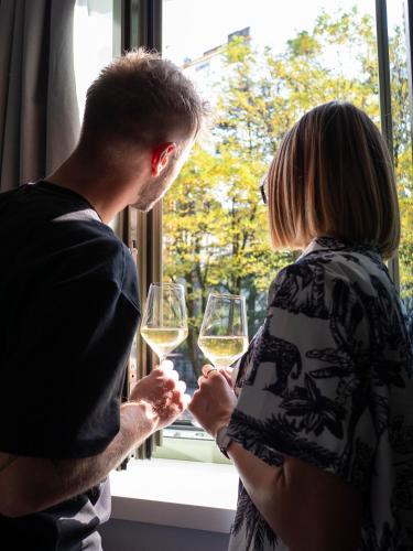 a man and woman holding wine glasses in front of a window at Innesti Rooms&Apartments - Le camere in Pergine Valsugana
