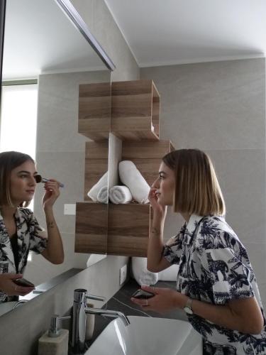 a woman brushing her teeth in a bathroom mirror at Innesti Rooms&Apartments - Le camere in Pergine Valsugana