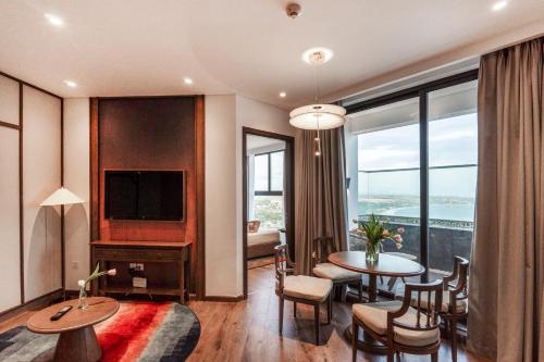 a room with a living room with a table and a television at Apec Mandala Harmony Resort & Spa in Mui Ne