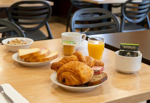 a table with a plate of bread and orange juice at B&B HOTEL Vannes Ouest Golfe du Morbihan in Vannes