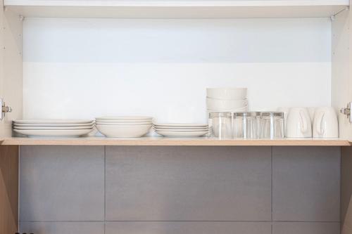 a shelf with plates and other dishes on it at 1BR The Sandstone Apartment by Blue Cloud Holidays in Sharjah Intl